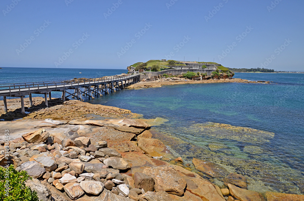 Famous Bare Island and its wooden footbridge in sunset light, Sydney Australia. It is a former military port connected with the mainland by the footbridge.