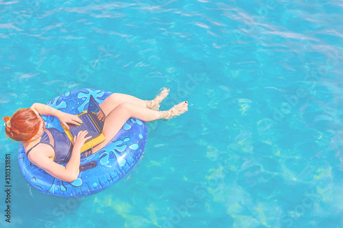 Beautiful young woman with on donuts and a desktop computer relaxing in the ocean.