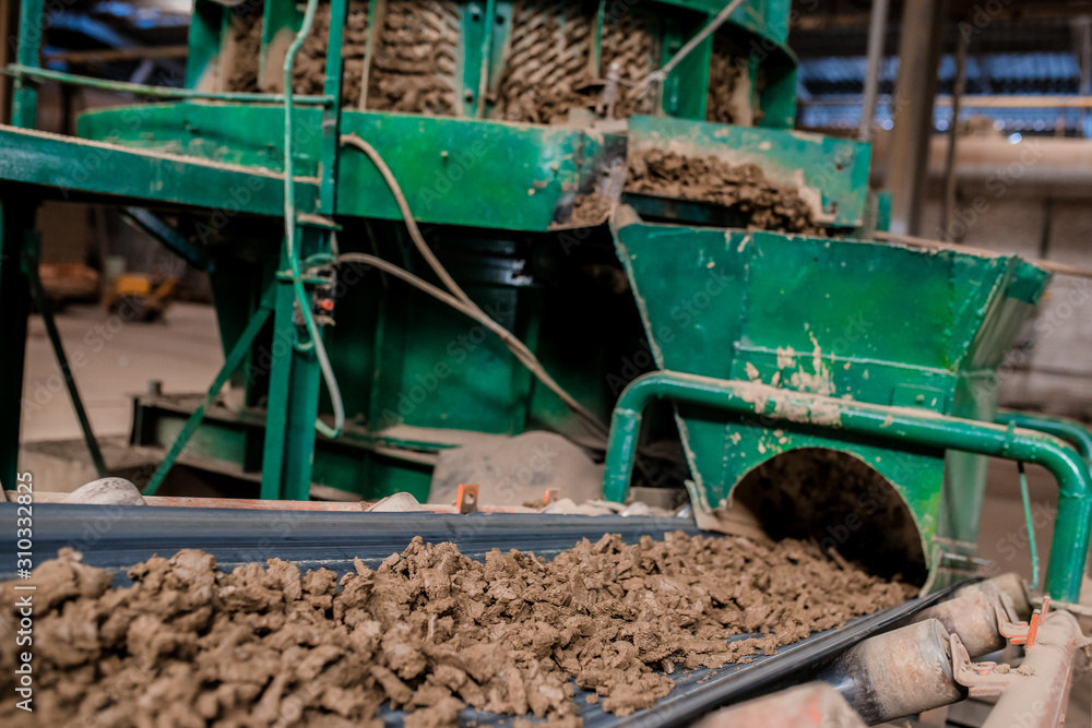 Obraz premium Plant for the production of bricks from clay. Plant for production building material with ready brick, construction industrial. Production of bricks on plant. Workflow, close-up. Many bricks
