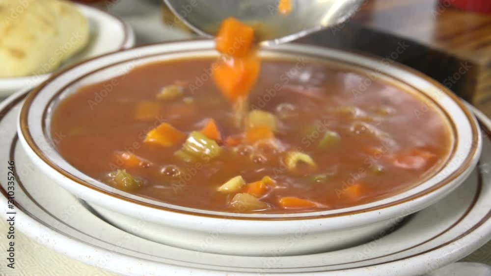 Spooning meatball soup into a bowl slow motion Spooning meatball soup into a bowl slow motion