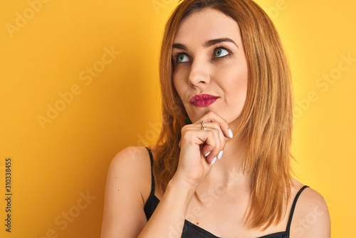 Close up of caucasian elegant woman over isolated yellow background serious face thinking about question, very confused idea