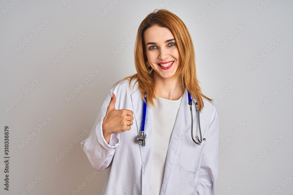 Redhead caucasian doctor woman wearing stethoscope over isolated background doing happy thumbs up gesture with hand. Approving expression looking at the camera with showing success. Redhead caucasian doctor woman wearing stethoscope over isolated background doing happy thumbs up gesture with hand. Approving expression looking at the camera with showing success.