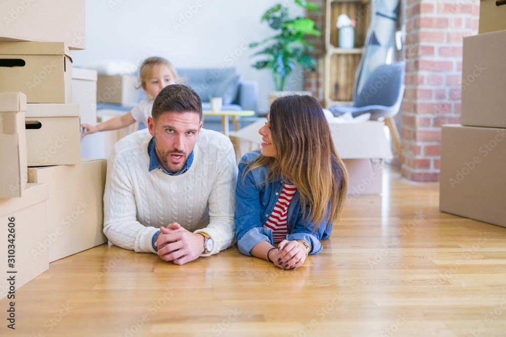 Beautiful famiily with kid lying down at new home around cardboard boxes Beautiful famiily with kid lying down at new home around cardboard boxes