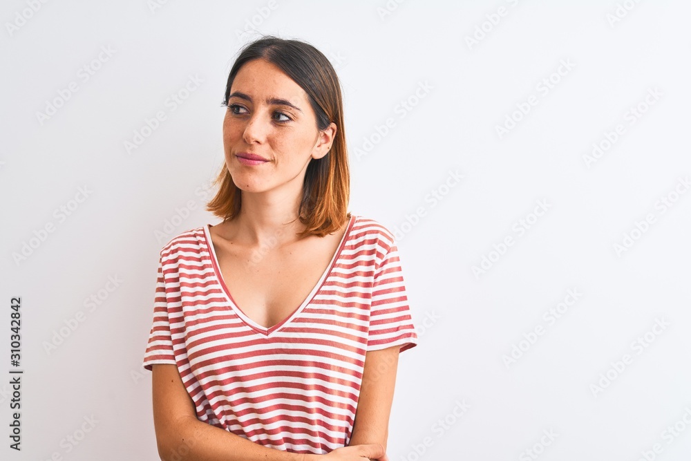 Beautiful redhead woman wearing casual striped red t-shirt over isolated background smiling looking to the side and staring away thinking. Beautiful redhead woman wearing casual striped red t-shirt over isolated background smiling looking to the side and staring away thinking.