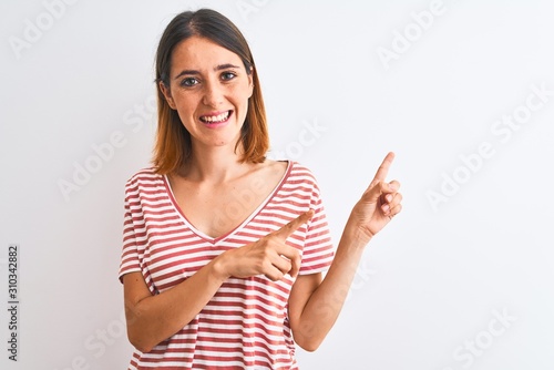 Beautiful redhead woman wearing casual striped red t-shirt over isolated background smiling and looking at the camera pointing with two hands and fingers to the side.