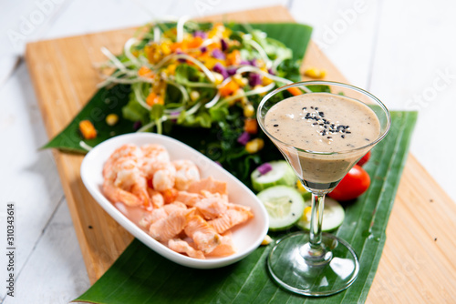 Fresh salad plate with shrimp  salmon  tomato and mixed greens  on wooden background .