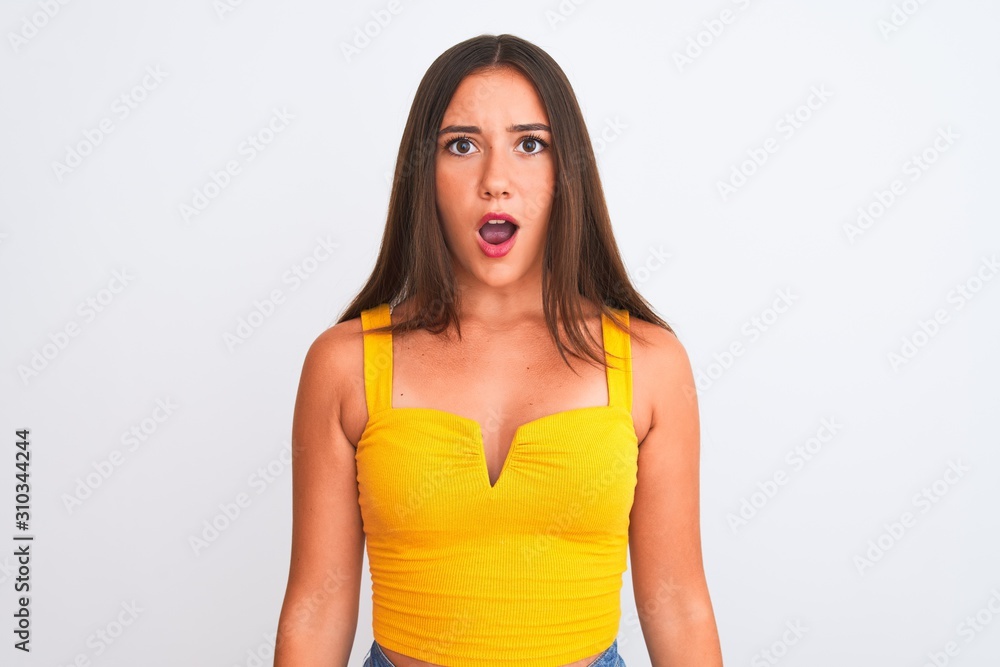 Young beautiful girl wearing yellow casual t-shirt standing over isolated white background afraid and shocked with surprise expression, fear and excited face. Young beautiful girl wearing yellow casual t-shirt standing over isolated white background afraid and shocked with surprise expression, fear and excited face.