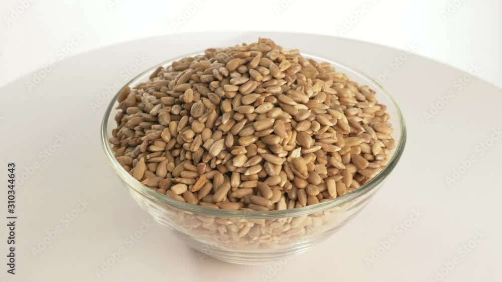 Nuts sunflower rotate are on a table in a plate. Snack in transparent dish on an isolated white background are spinning moving. Delicious and healthy protein-rich diet food. Nuts sunflower rotate are on a table in a plate. Snack in transparent dish on an isolated white background are spinning moving. Delicious and healthy protein-rich diet food.
