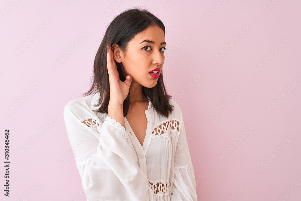 Young chinese woman wearing summer shirt standing over isolated pink background smiling with hand over ear listening an hearing to rumor or gossip. Deafness concept. Young chinese woman wearing summer shirt standing over isolated pink background smiling with hand over ear listening an hearing to rumor or gossip. Deafness concept.