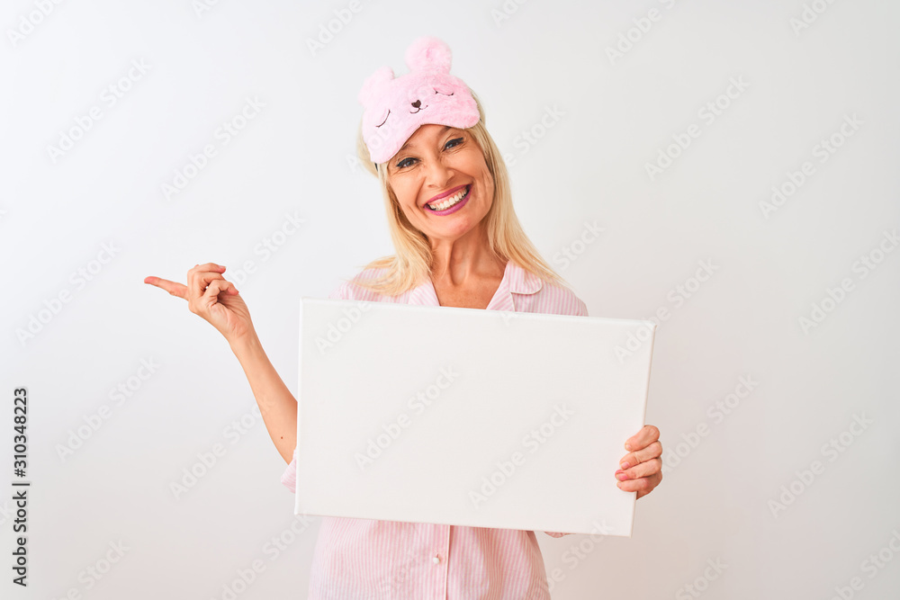 Middle age woman wearing sleep mask pajama holding banner over isolated white background very happy pointing with hand and finger to the side Middle age woman wearing sleep mask pajama holding banner over isolated white background very happy pointing with hand and finger to the side
