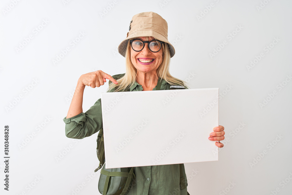Senior hiker woman wearing canteen hat holding banner over isolated white background with surprise face pointing finger to himself Senior hiker woman wearing canteen hat holding banner over isolated white background with surprise face pointing finger to himself