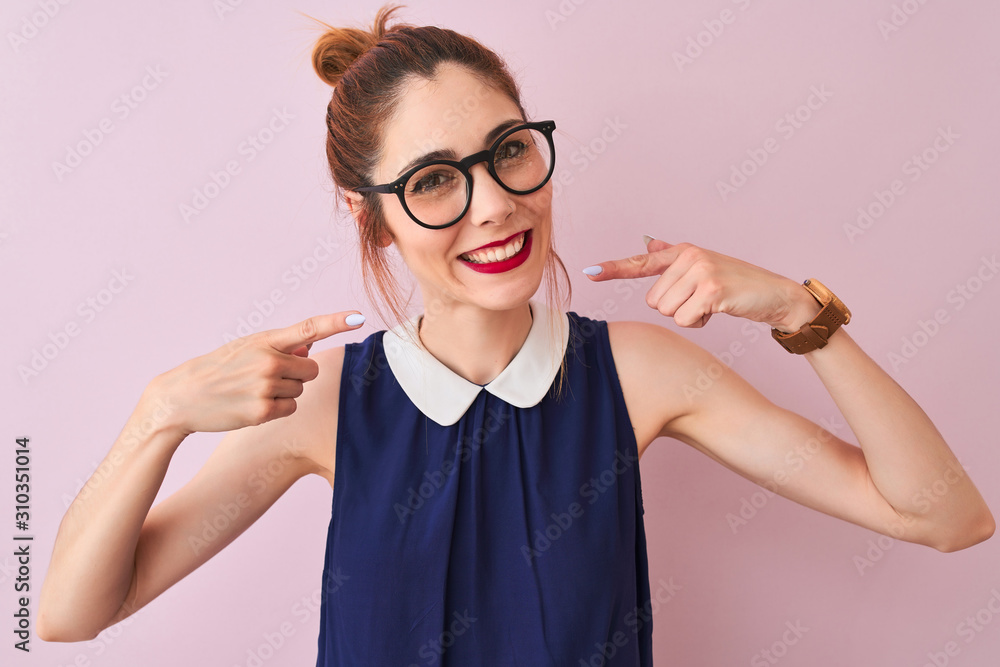 Redhead woman with pigtail wearing elegant dress and glasses over isolated pink background smiling cheerful showing and pointing with fingers teeth and mouth. Dental health concept. Redhead woman with pigtail wearing elegant dress and glasses over isolated pink background smiling cheerful showing and pointing with fingers teeth and mouth. Dental health concept.