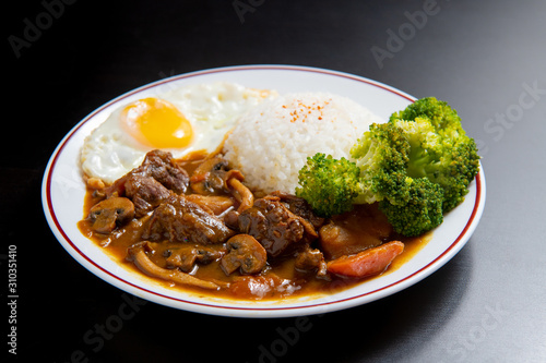 beef Curry Rice on black wooden background ( Onsen tamago, Potato, enoki mushroom, onion, broccoli, Japanese style)