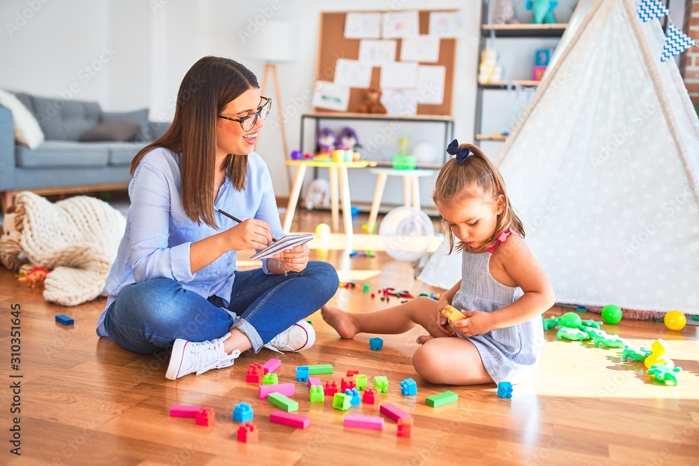 Fototapeta premium Młoda terapeuta mówi i leczy dziecko, doradca i korekta zachowania w kasie pedagoga, robi notatki na schowku