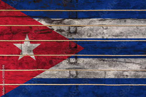 National flag of Cuba on a wooden wall background. The concept of national pride and a symbol of the country. Flags painted on a wooden fence with a rope