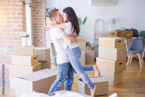 Young beautiful couple hugging at new home around cardboard boxes © Krakenimages.com