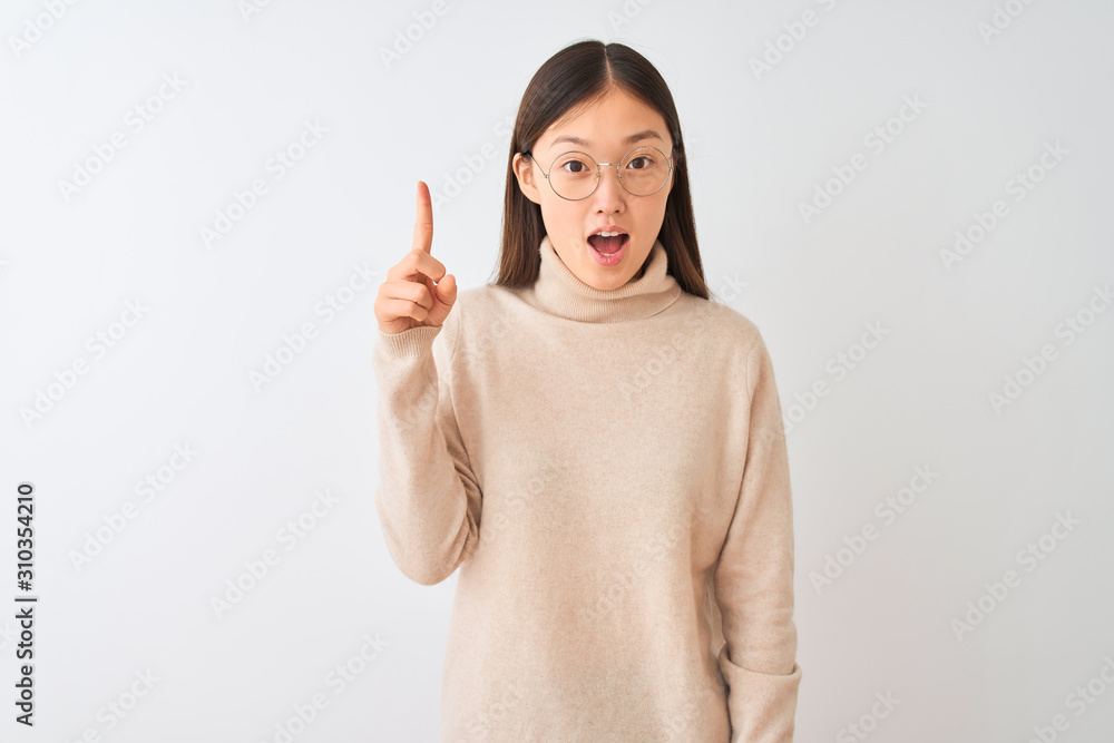 Young chinese woman wearing turtleneck sweater and glasses over isolated white background pointing finger up with successful idea. Exited and happy. Number one. Young chinese woman wearing turtleneck sweater and glasses over isolated white background pointing finger up with successful idea. Exited and happy. Number one.