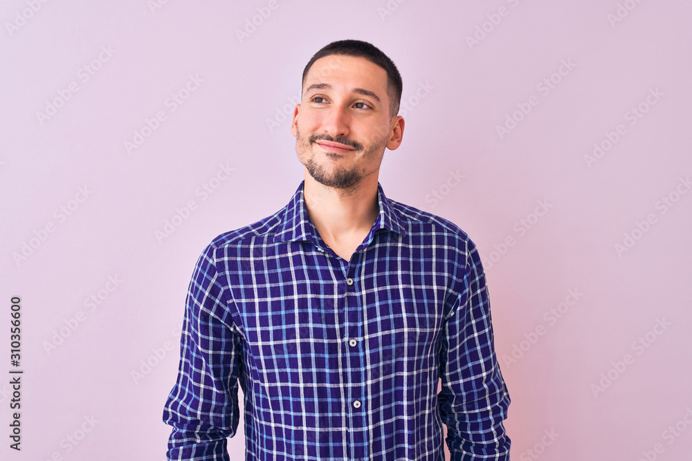 Young handsome man standing over isolated background smiling looking to the side and staring away thinking. Young handsome man standing over isolated background smiling looking to the side and staring away thinking.