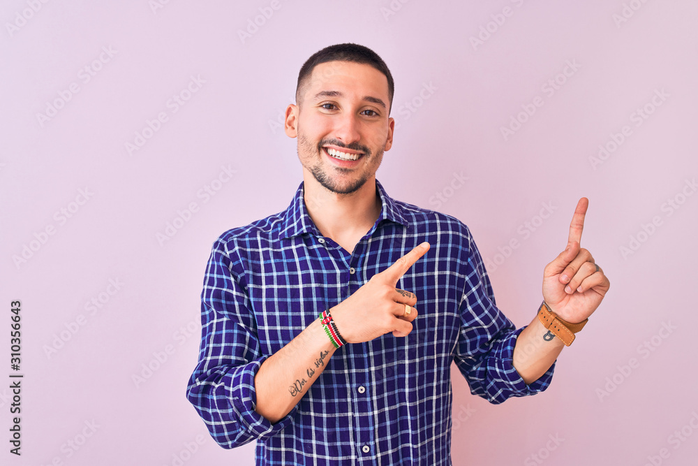 Naklejka premium Young handsome man standing over isolated background smiling and looking at the camera pointing with two hands and fingers to the side.