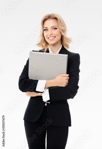 Portrait of young happy smiling businesswoman in black confident suit, with grey folder, with copy space for slogan or text, isolated over grey background