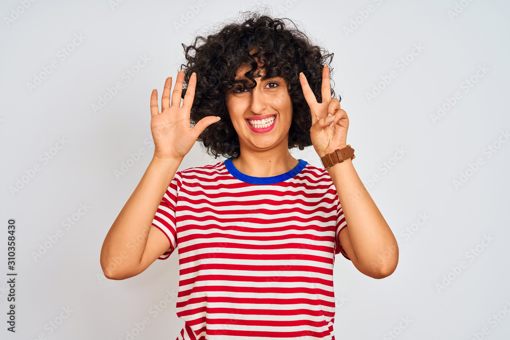 Young arab woman with curly hair wearing striped t-shirt over isolated white background showing and pointing up with fingers number seven while smiling confident and happy. Young arab woman with curly hair wearing striped t-shirt over isolated white background showing and pointing up with fingers number seven while smiling confident and happy.