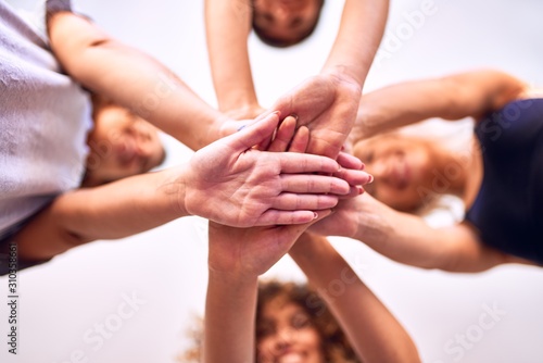 Young beautiful group of sportswomen standing shaking hands after class of yoga at gym