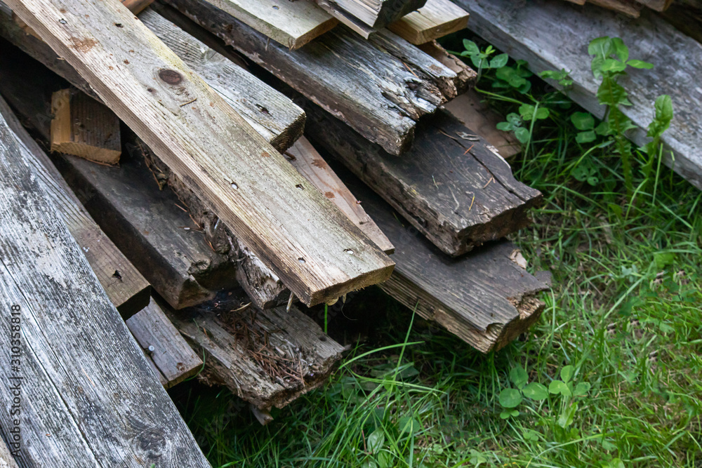 piles of mismatched old broken deck boards laying in grass