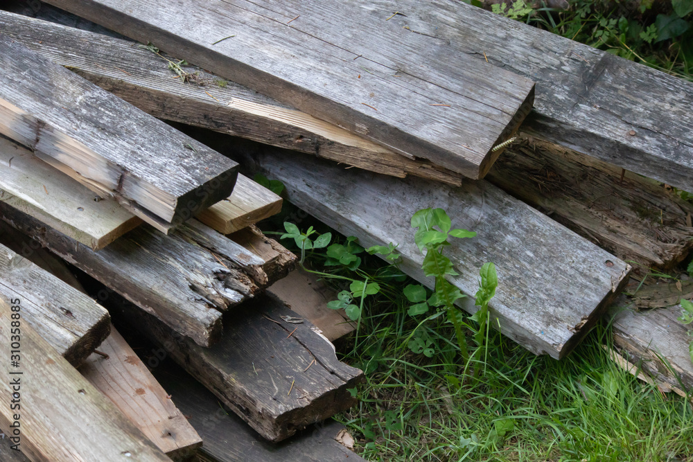piles of mismatched old broken deck boards laying in grass piles of mismatched old broken deck boards laying in grass