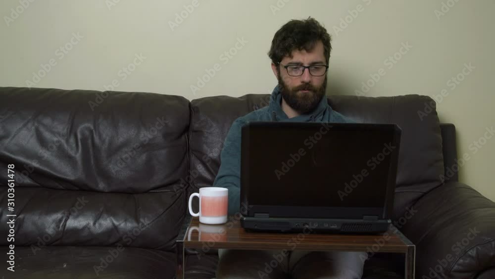 Casual Man Sitting on Comfortable Sofa and Working on Computer Casual Man Sitting on Comfortable Sofa and Working on Computer