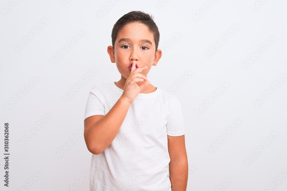 Beautiful kid boy wearing casual t-shirt standing over isolated white background asking to be quiet with finger on lips. Silence and secret concept. Beautiful kid boy wearing casual t-shirt standing over isolated white background asking to be quiet with finger on lips. Silence and secret concept.