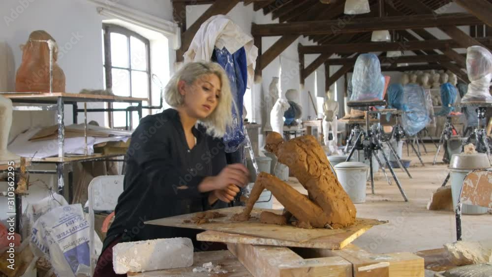 Sculptress Sculptor is sculpting realistic, figurative model in large studio Sculptress Sculptor is sculpting realistic, figurative model in large studio