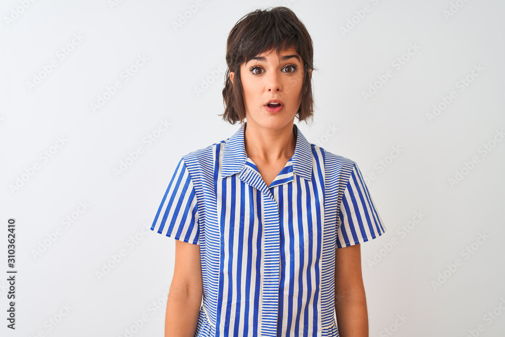 Young beautiful woman wearing blue striped shirt standing over isolated white background afraid and shocked with surprise expression, fear and excited face.