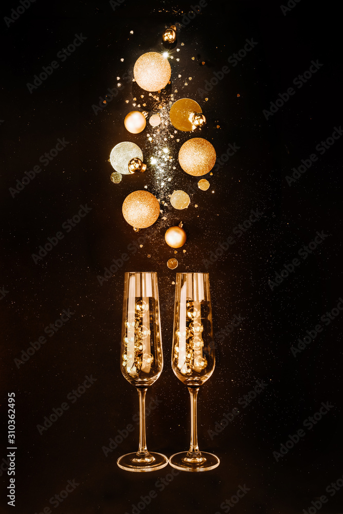 Christmas composition. Glasses with champagne wine from gold festive decorations on a black background with glitters. The concept of a party and a festive feast Christmas composition. Glasses with champagne wine from gold festive decorations on a black background with glitters. The concept of a party and a festive feast