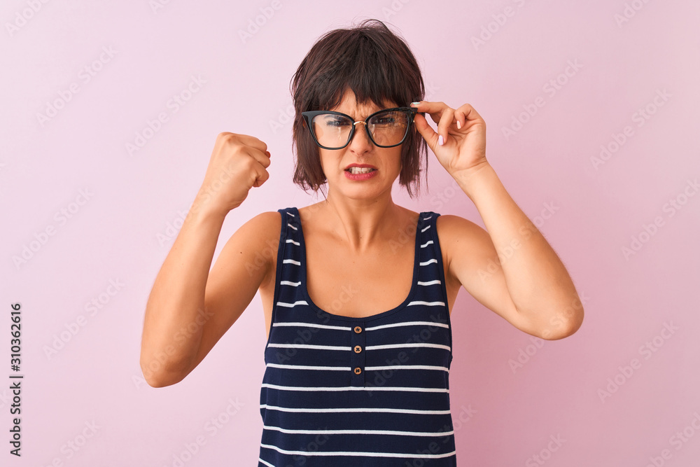 Beautiful woman wearing striped t-shirt and glasses standing over isolated pink background annoyed and frustrated shouting with anger, crazy and yelling with raised hand, anger concept Beautiful woman wearing striped t-shirt and glasses standing over isolated pink background annoyed and frustrated shouting with anger, crazy and yelling with raised hand, anger concept