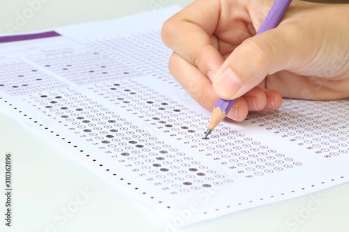 Hand student filling out answers to purple answer sheet with purple pencil. photo