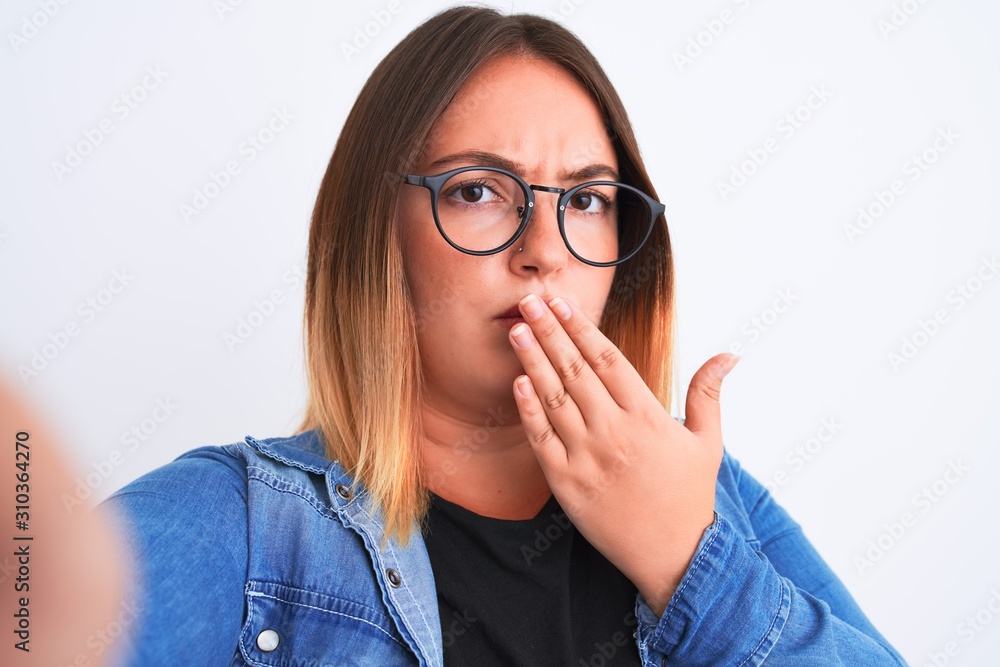 Beautiful woman wearing denim shirt and glasses make selfie over isolated white background cover mouth with hand shocked with shame for mistake, expression of fear, scared in silence, secret concept Beautiful woman wearing denim shirt and glasses make selfie over isolated white background cover mouth with hand shocked with shame for mistake, expression of fear, scared in silence, secret concept