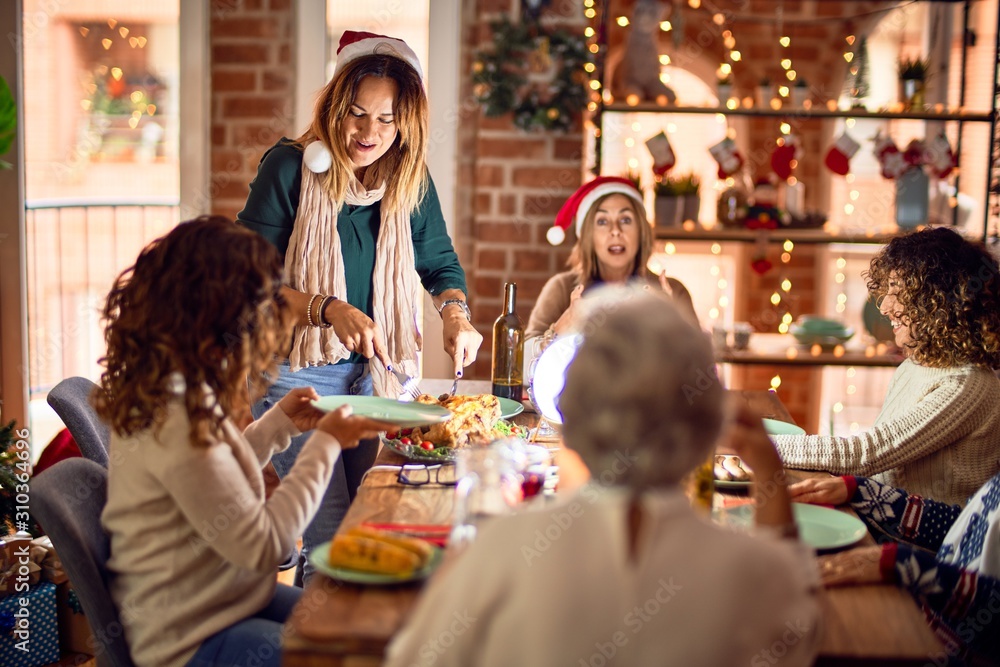 Beautiful group of women smiling happy and confident. Carving roasted turkey celebrating christmas at home