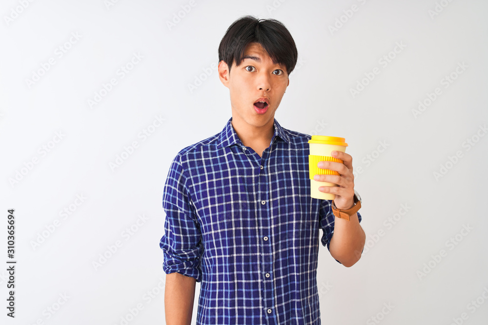 Young chinese man drinking take away coffee standing over isolated white background scared in shock with a surprise face, afraid and excited with fear expression Young chinese man drinking take away coffee standing over isolated white background scared in shock with a surprise face, afraid and excited with fear expression