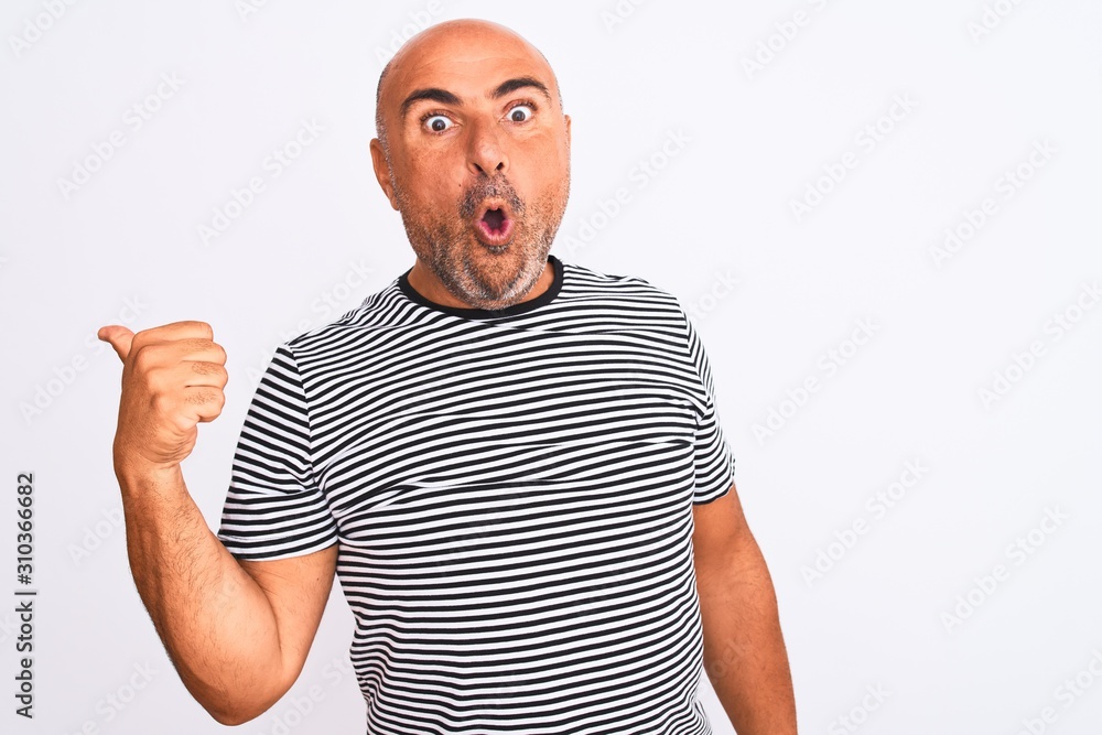 Middle age handsome man wearing striped navy t-shirt over isolated white background Surprised pointing with hand finger to the side, open mouth amazed expression. Middle age handsome man wearing striped navy t-shirt over isolated white background Surprised pointing with hand finger to the side, open mouth amazed expression.