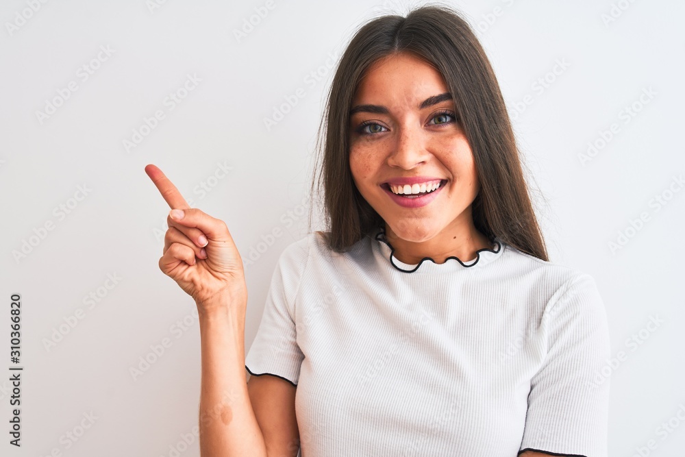 Young beautiful woman wearing casual t-shirt standing over isolated white background very happy pointing with hand and finger to the side Young beautiful woman wearing casual t-shirt standing over isolated white background very happy pointing with hand and finger to the side