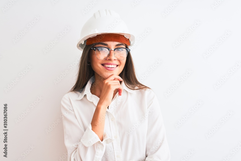 Young beautiful architect woman wearing helmet and glasses over isolated white background looking confident at the camera smiling with crossed arms and hand raised on chin. Thinking positive.