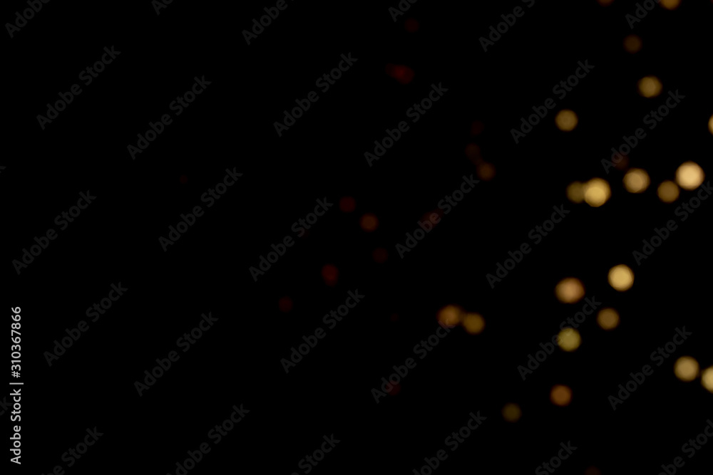 Golden glitter bokeh lights on black background, unfocused. Holiday time. Golden glitter bokeh lights on black background, unfocused. Holiday time.