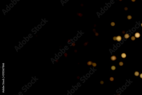 Golden glitter bokeh lights on black background, unfocused. Holiday time.