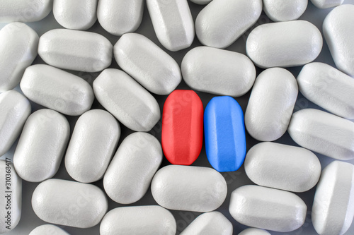 Red and blue pills between similar shaped white pills. Choice concept. Close-up, top view.