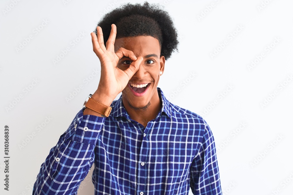 Young african american man wearing casual shirt standing over isolated white background doing ok gesture with hand smiling, eye looking through fingers with happy face. Young african american man wearing casual shirt standing over isolated white background doing ok gesture with hand smiling, eye looking through fingers with happy face.