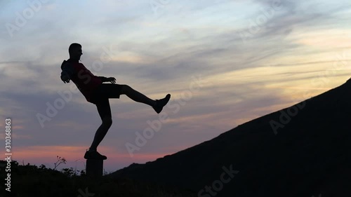 Wallpaper Mural Dark silhouette of a hiker balancing on a stone in evening mountains. Torontodigital.ca