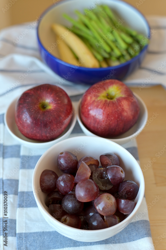 Grapes, apples, vegetables and dishcloths are on a wooden table Grapes, apples, vegetables and dishcloths are on a wooden table