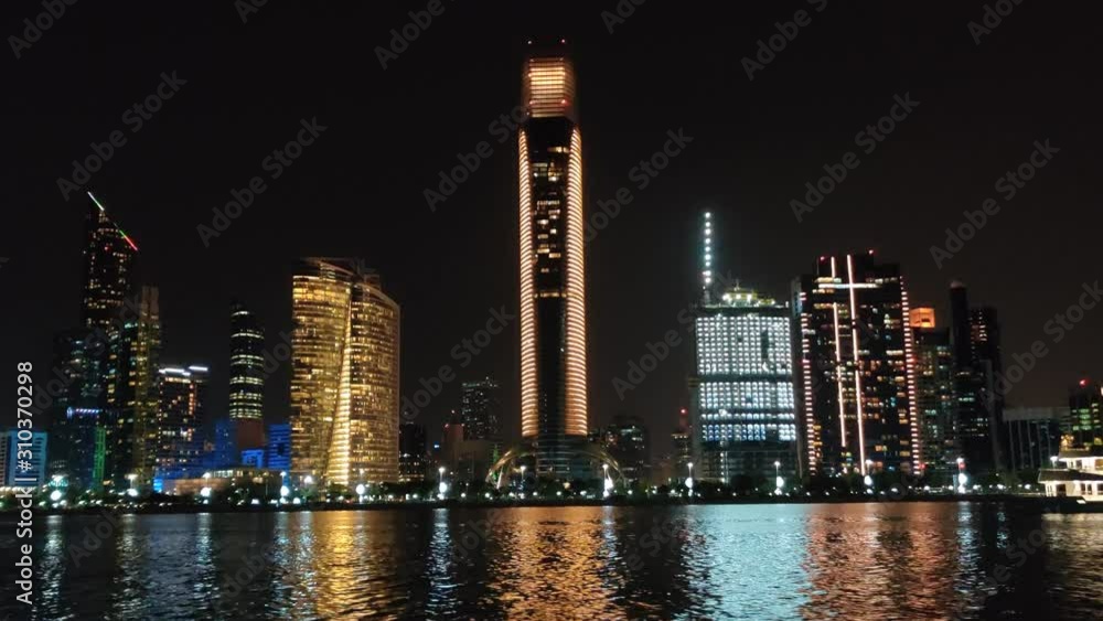 Futuristic city skyline with screen projectors - Beautiful view of Abu Dhabi city beach and landmarks from the famous corniche road - Night city lights Futuristic city skyline with screen projectors - Beautiful view of Abu Dhabi city beach and landmarks from the famous corniche road - Night city lights