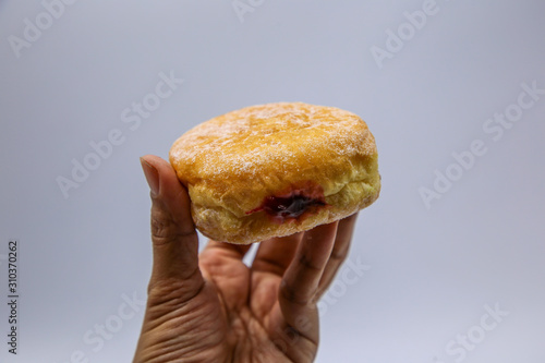 Hand catch Strawberry jam stuffed donut Isolated on White Background