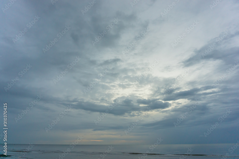 dark cloudy sky and sea. there is light shine through the cloud.